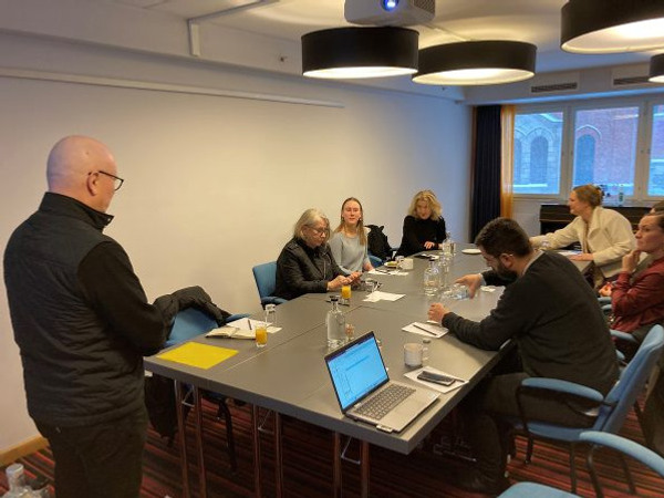 Foto av konferensbord med människor som sitter runt.