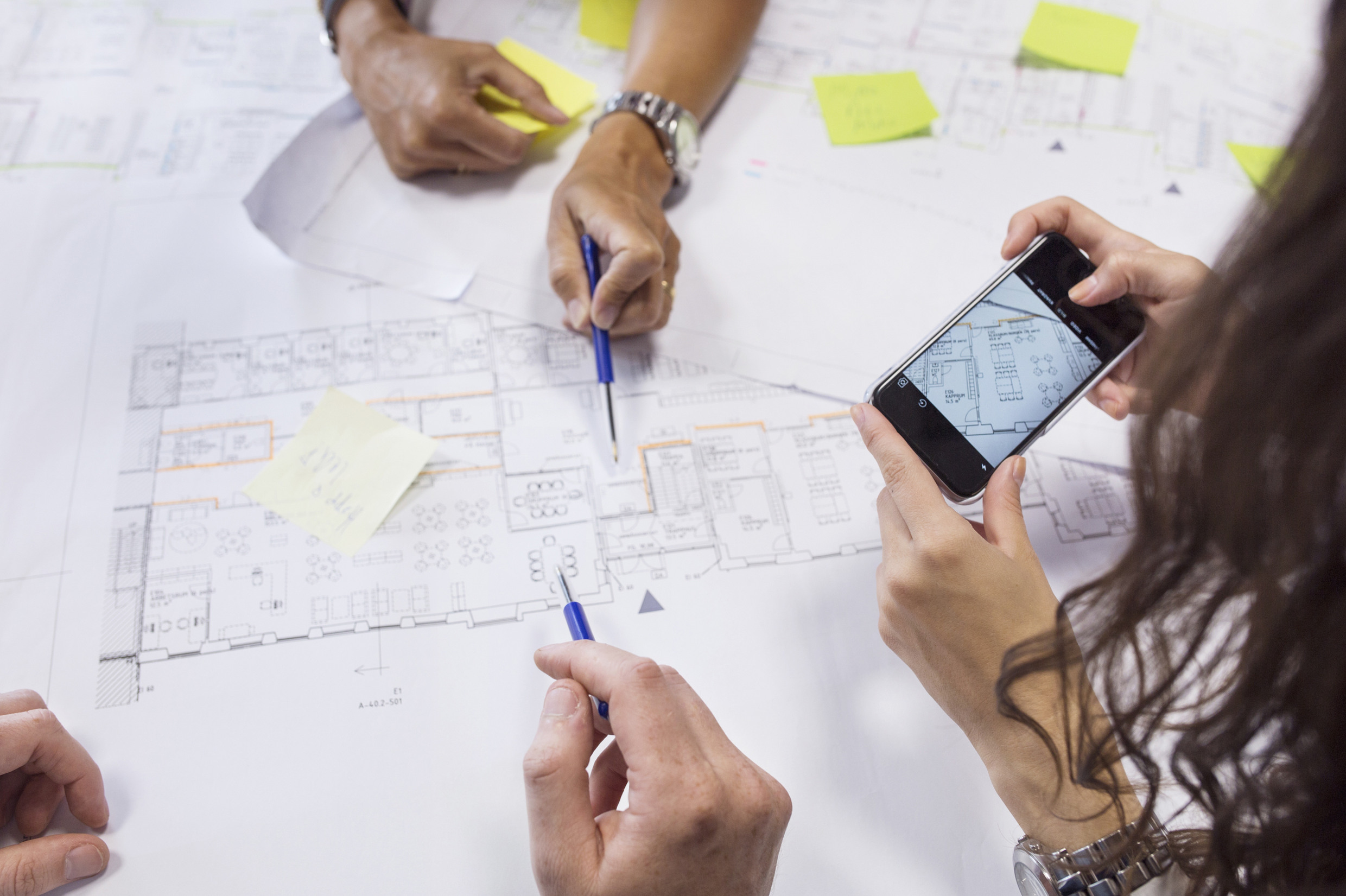 Tre personer arbetar vid en ritning.