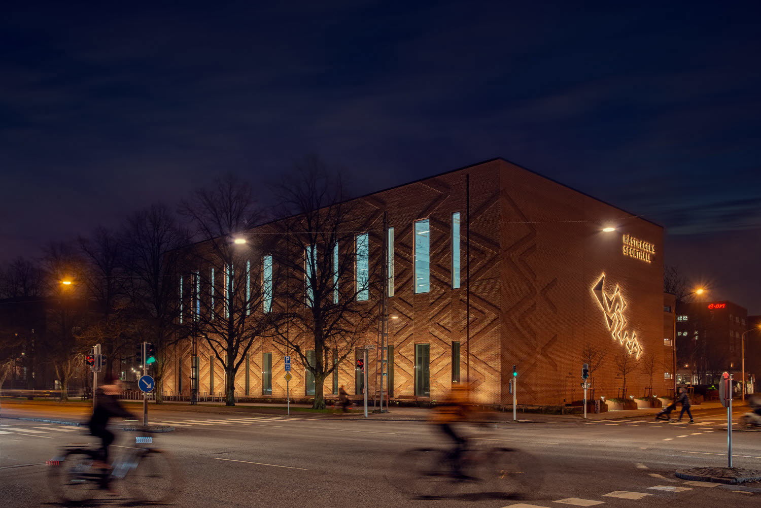 Upplyst fasad där belyssningen gör att teglets mönster framhävs.