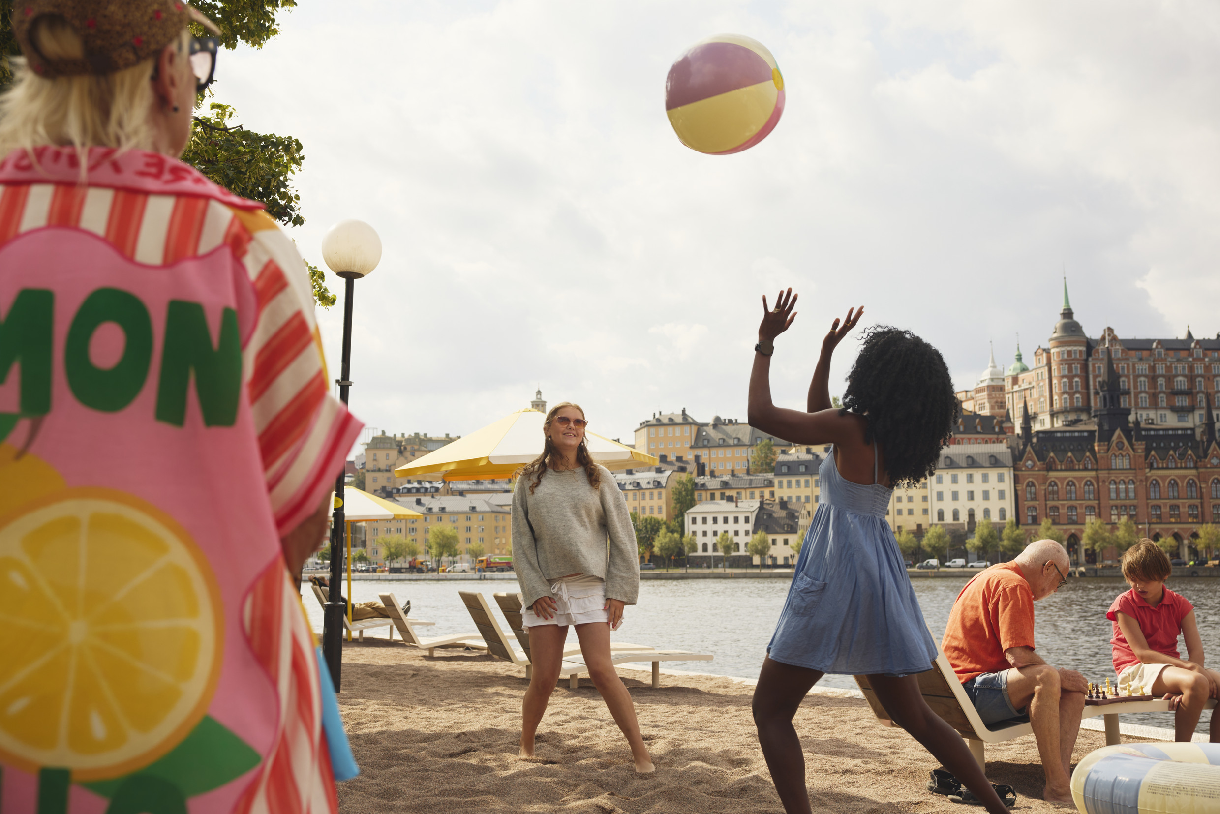 Fem personer spelar spel på en strand i en stad