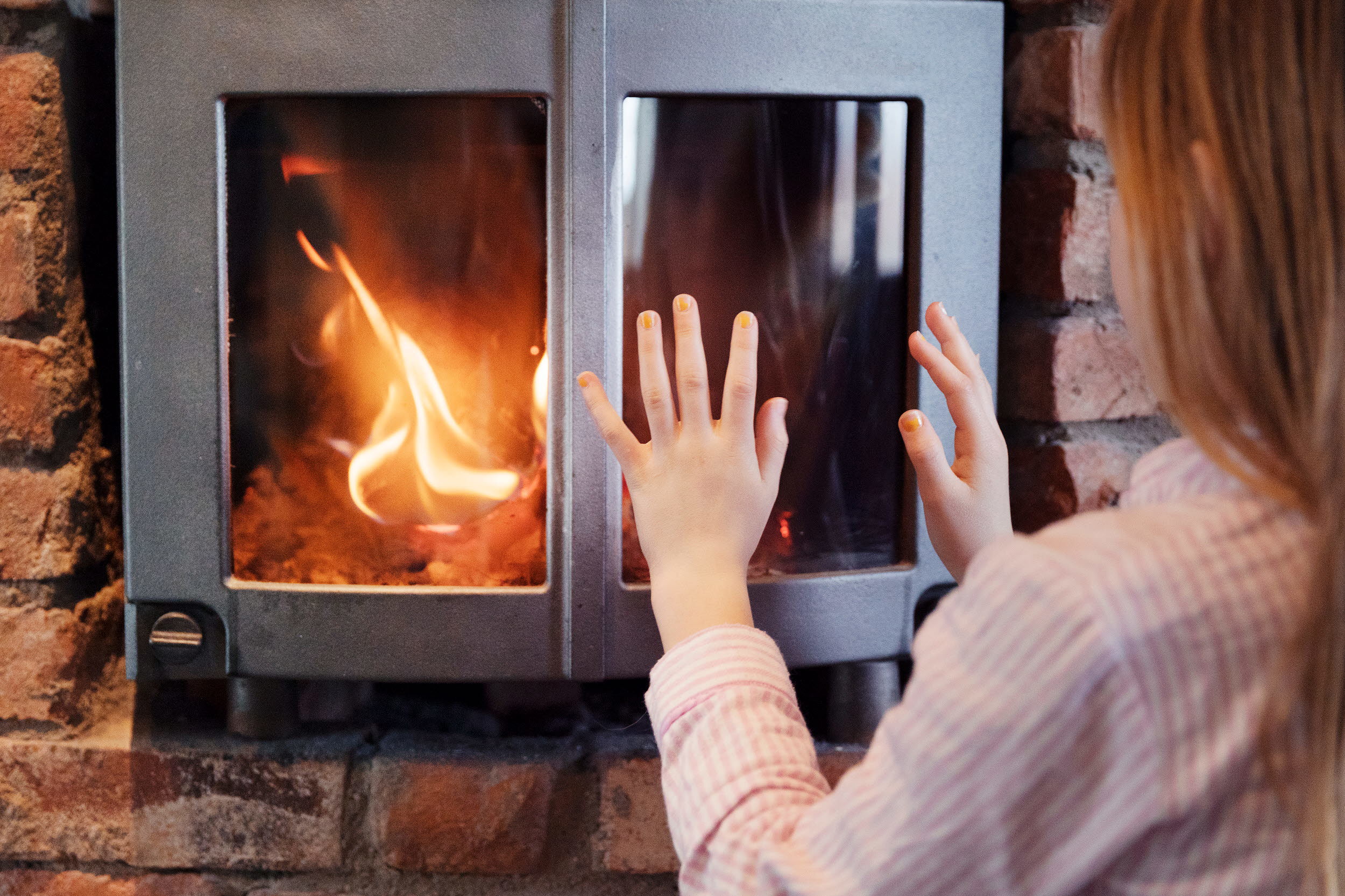 Foto på person framför kamin med brasa i.