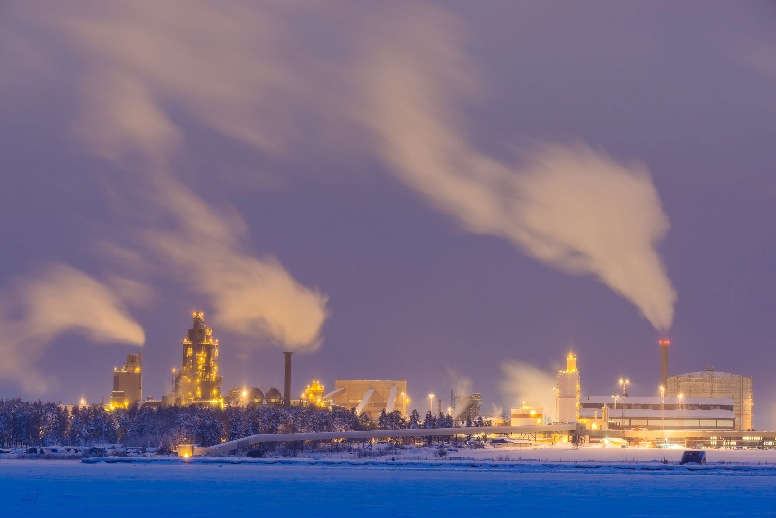 Fabriker som släpper ut rök i skymning.