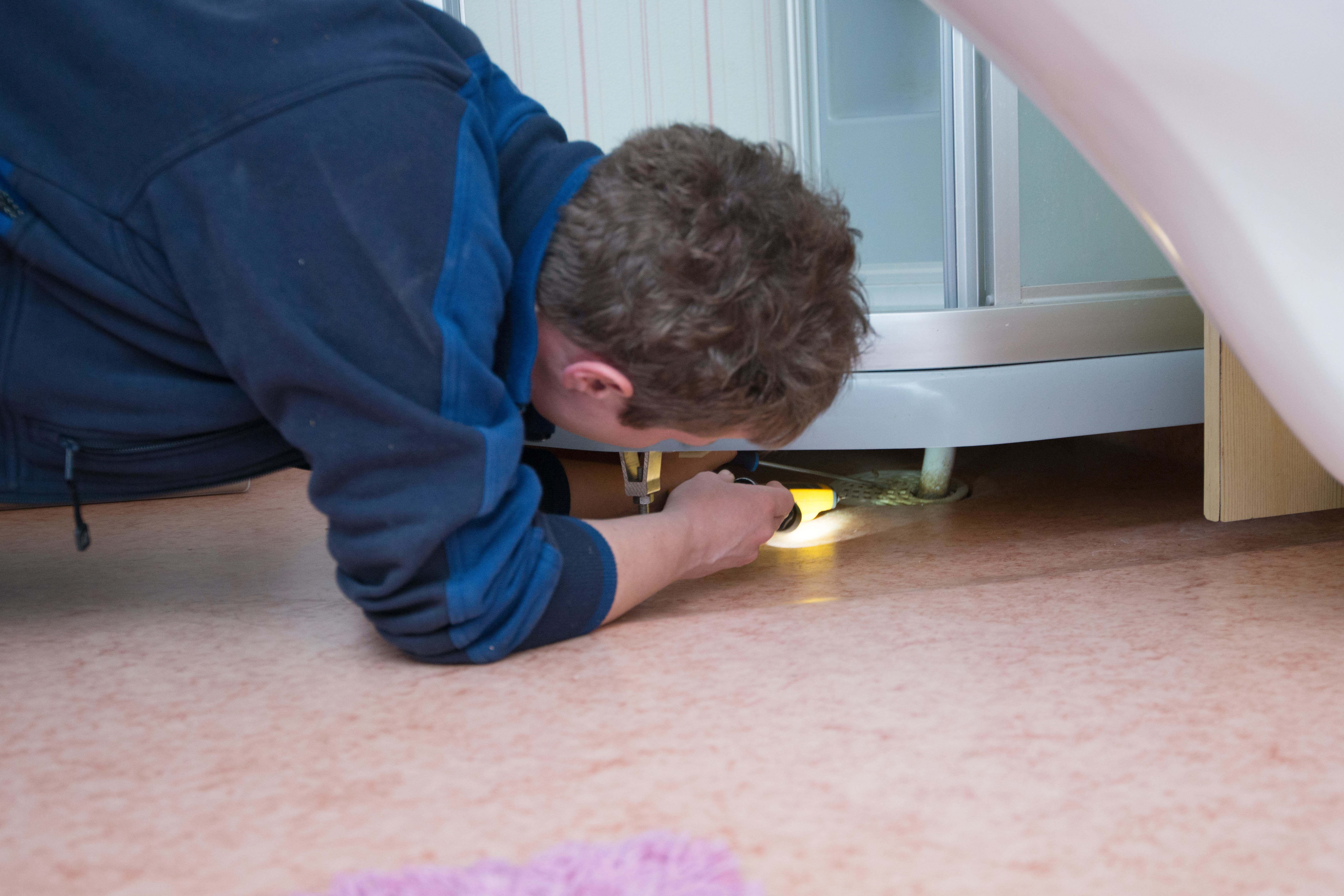 Foto på kontrollperson som tittar under en duschkabin.