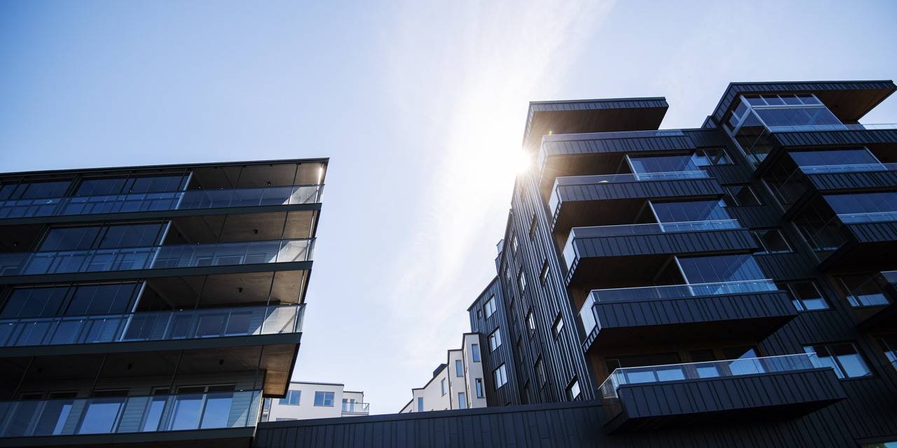 Två byggnader med balkonger och sol.