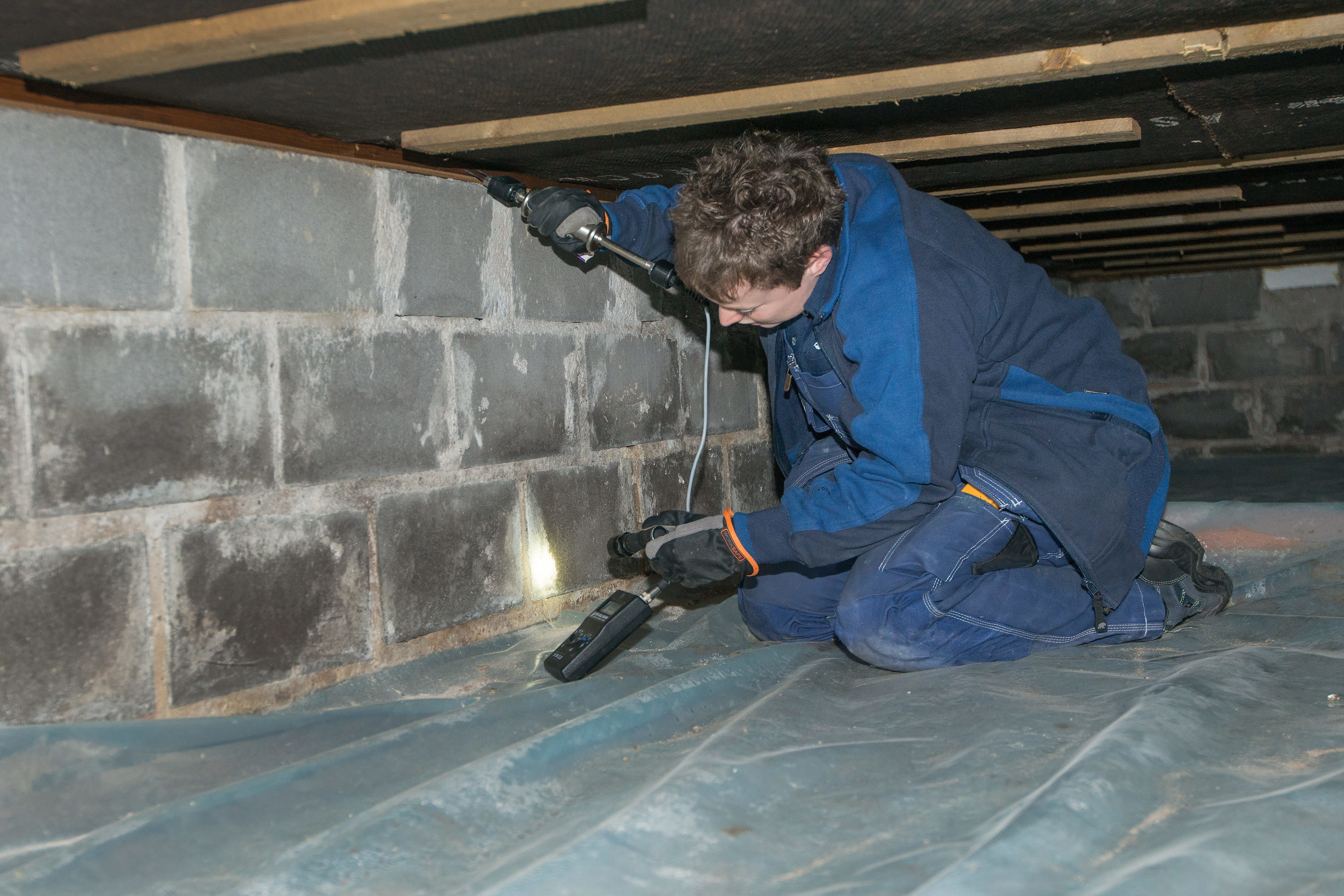 Kvinna som mäter fukt i källare.