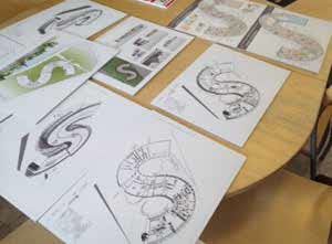 Foto på ett bord där olika ritningar och skisser ligger utlagda.