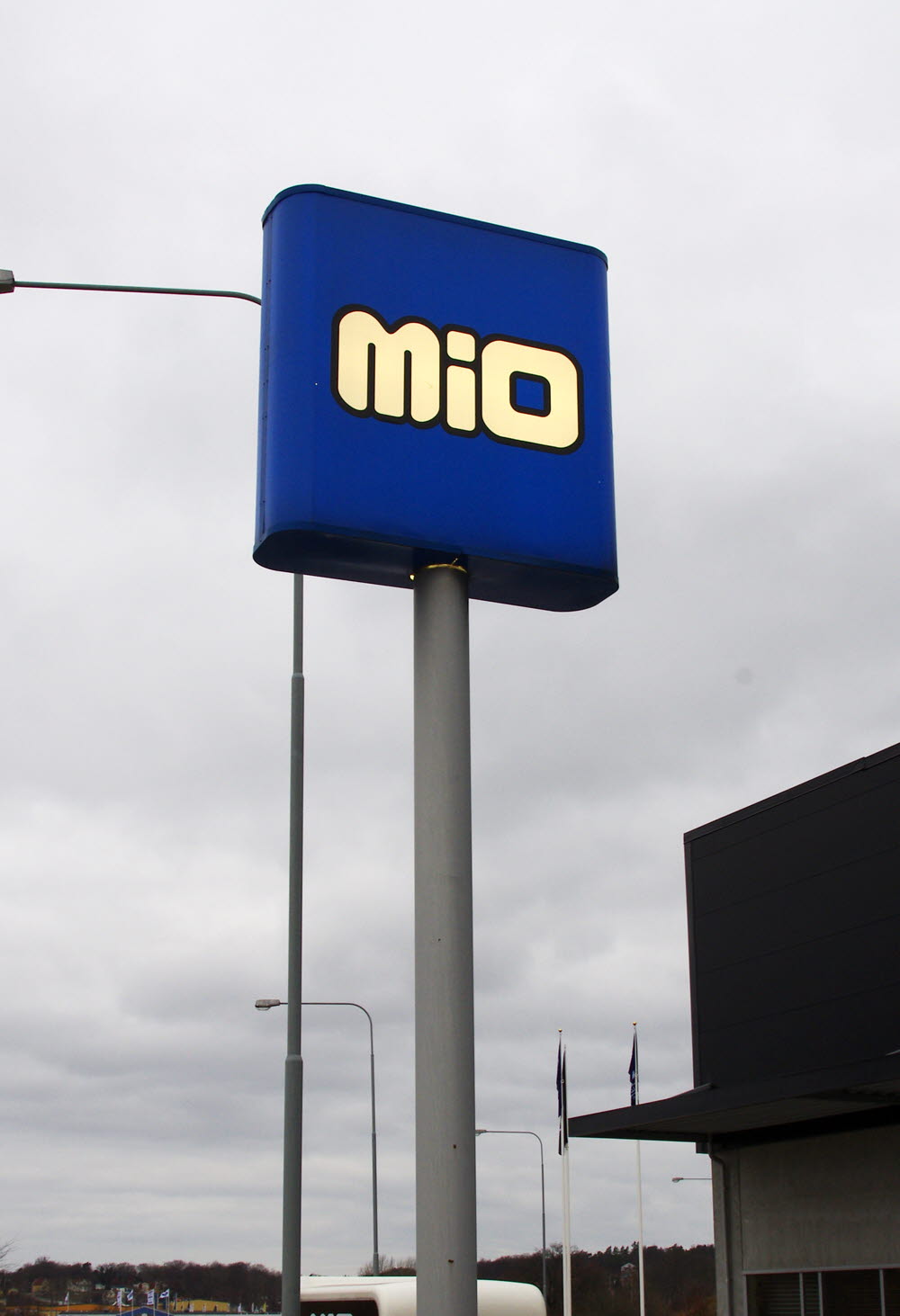 Foto av en hög blå skylt på stolpe med texten MIO utanför en möbelaffär..
