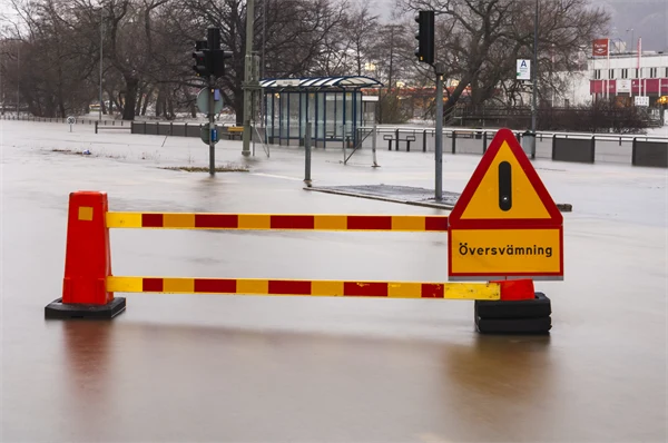 Översvämmad gata med varningsskyltar.