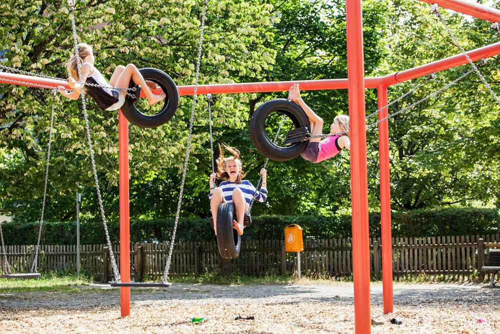 Barn som leker i en röd klätterställning/gungställning.