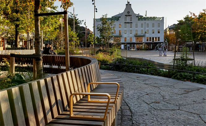 En lång rundad bänk med två handtag i en park. Foto: Werner Nystrand