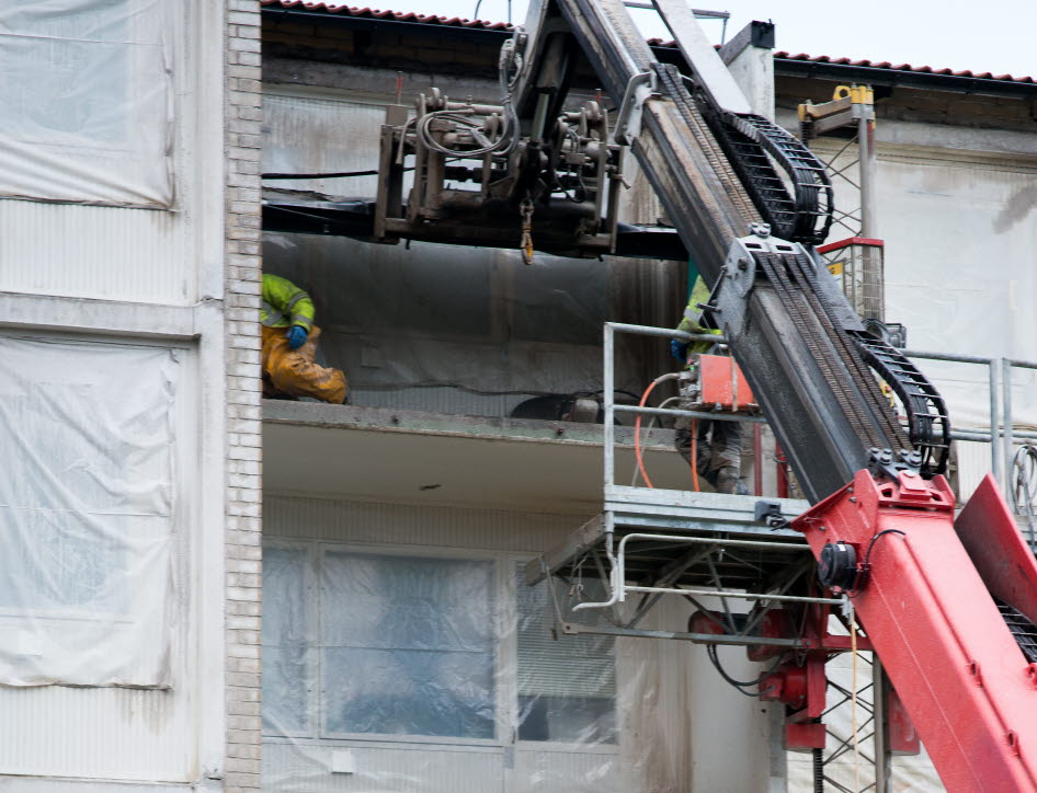 Byggarbetare arbetar med att montera fönster på en byggnad med hjälp av en kranbil. Foto: Franz Feldmanis