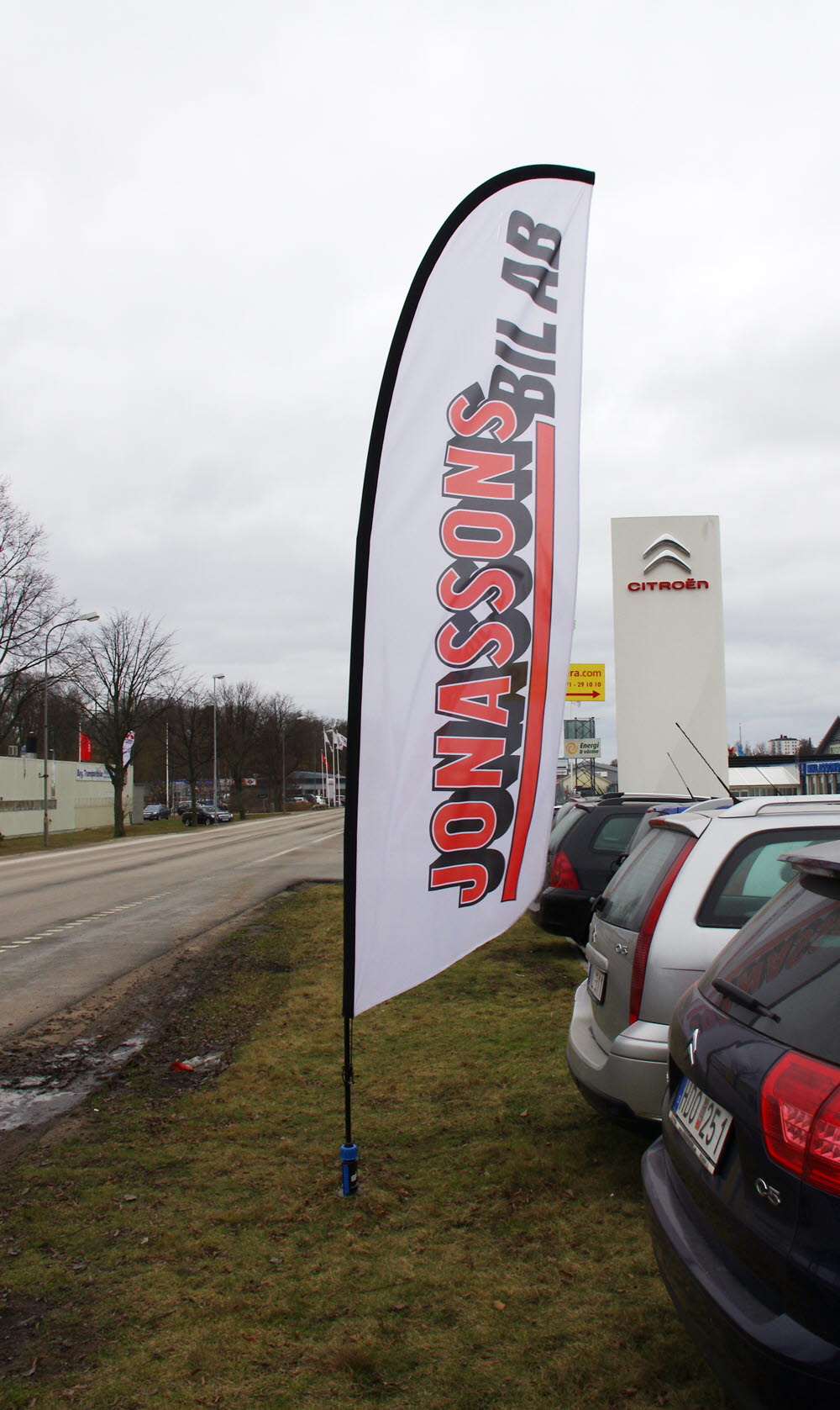 Foto på en fjäderflagga med texten Jonassons bil AB vid bilfirma. 