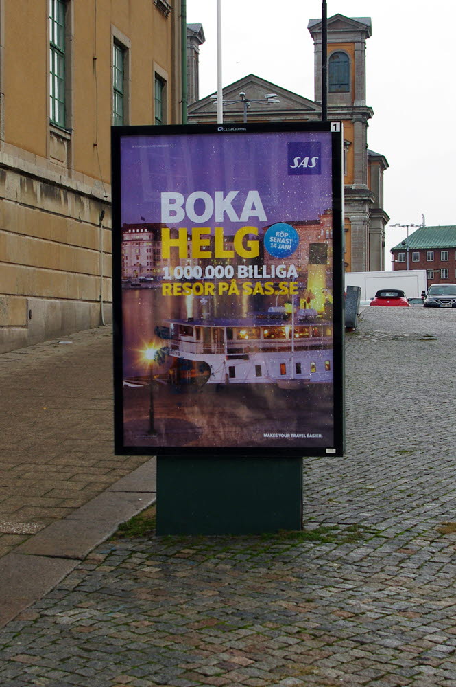 Foto på en reklamtavla med reklam för SAS ståendes på ett torg..