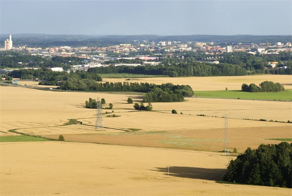 Flygfoto av landskap med stora sädesfält och en tätort med bostäder, handelsområde och industri. 