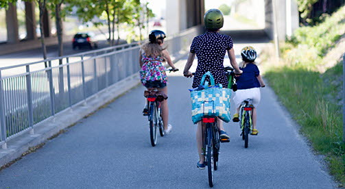 En kvinna och två barn cyklar på en cykelväg