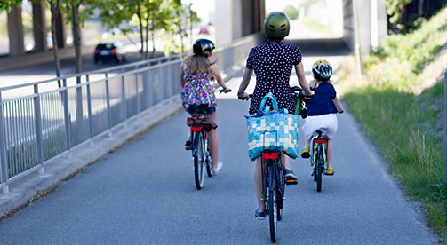 En kvinna och två barn cyklar på en cykelväg