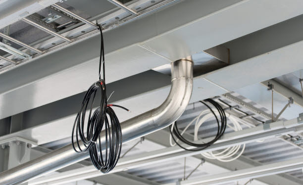 Foto på innertak i fastighet med kablar, rör och ventilation.