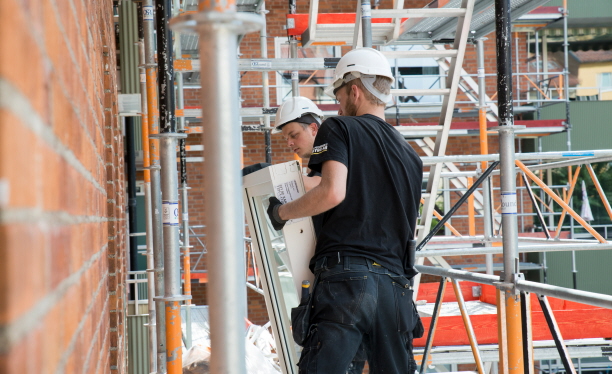 Två personer som byter fönster på ett flerbostadshus. Foto: Franz Feldmanis.