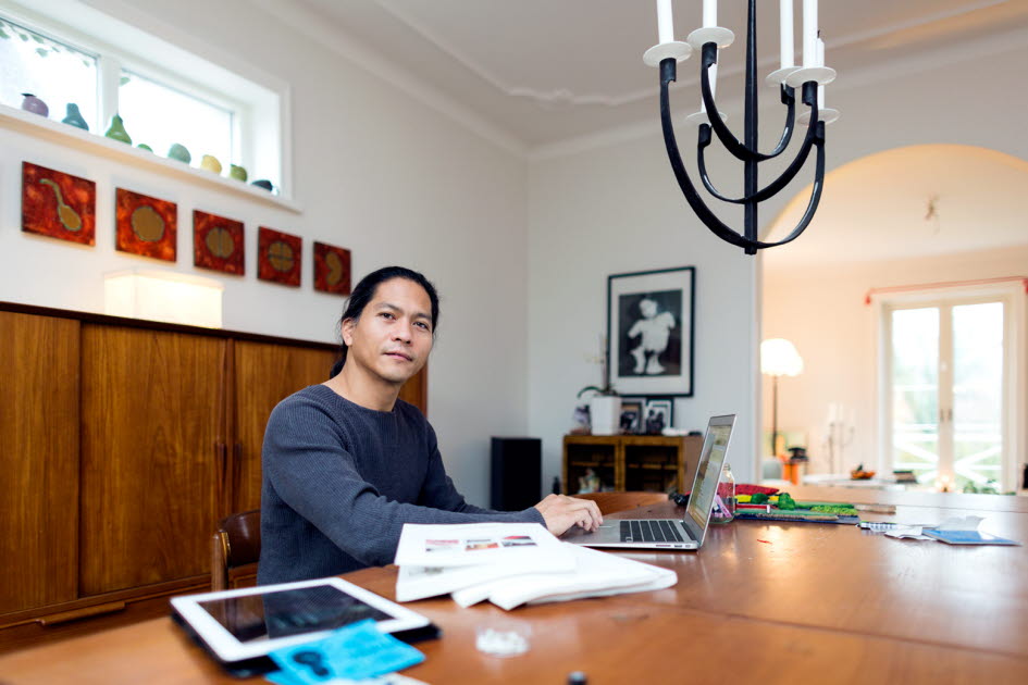 Man sitter vid ett bord och arbetar med dator, papper och iPad. Foto: Peter Kroon