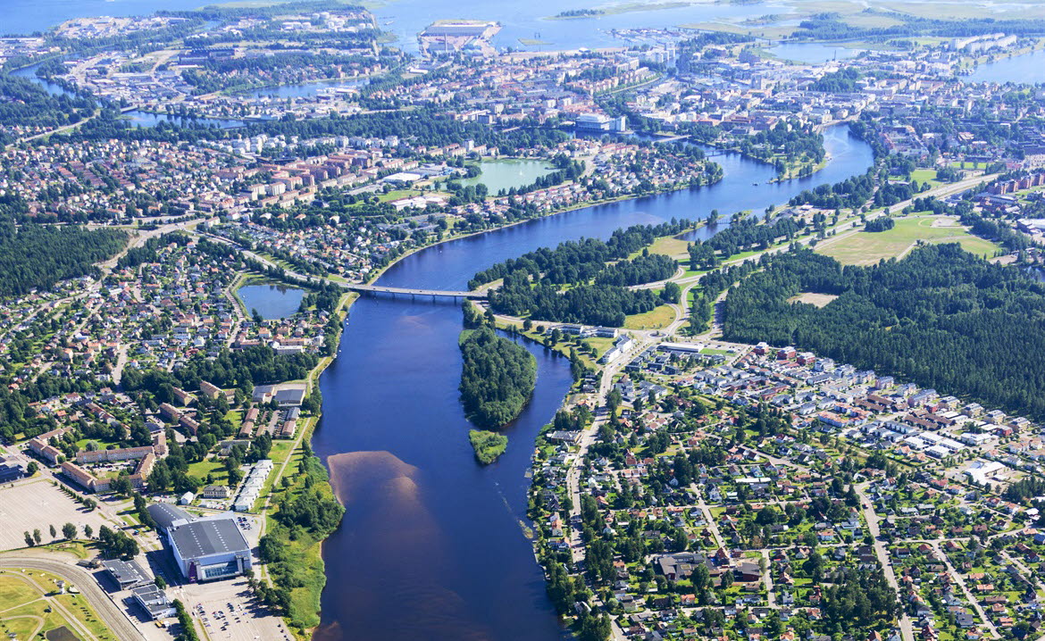 Bilden visar ett flygfoto över Karlstad med Klarälven, Vänern, olika typer av bebyggelse, skog, grönområden och parker.
