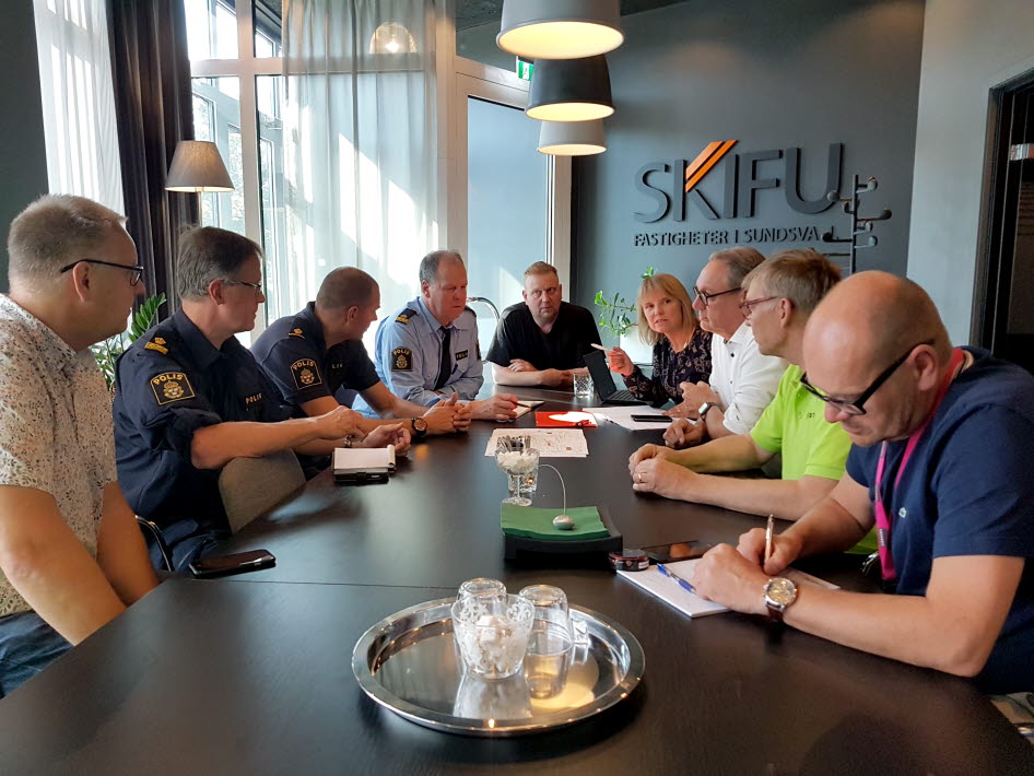 Bilden visar ett stationsrådsmöte med bred samverkan mellan representanter från fastighetsägaren, kommunen, Polisen, vaktbolag, näringsidkare, stadskärneutvecklare och lokal kollektivtrafik. Runt ett bord sitter åtta män och en kvinna.