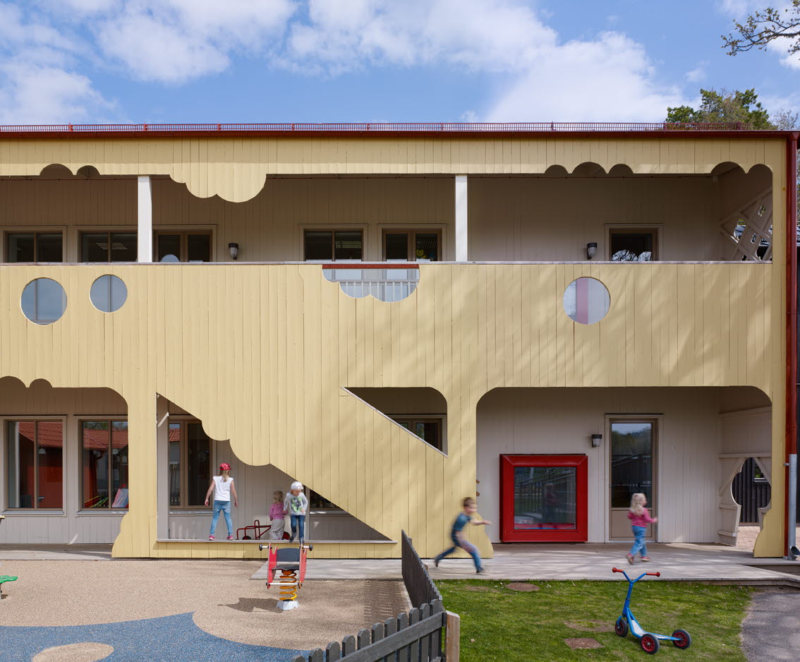 Barn som leker på skolgården. Närmast skolan är zonen närmast byggnaden skyddad av tak.