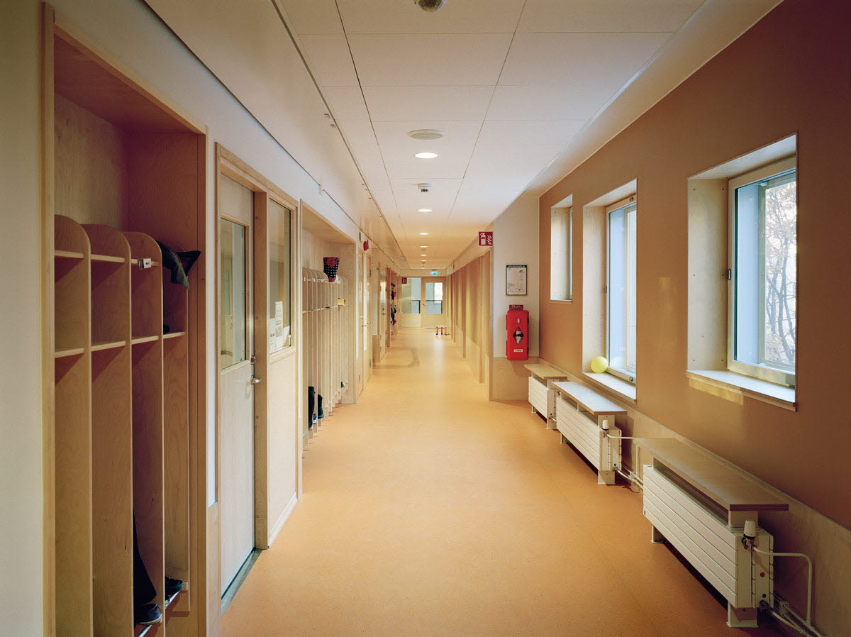 En lång och ljus korridor med bänkar och klädhänngare.