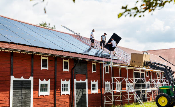 Personer monterar solceller på tak.