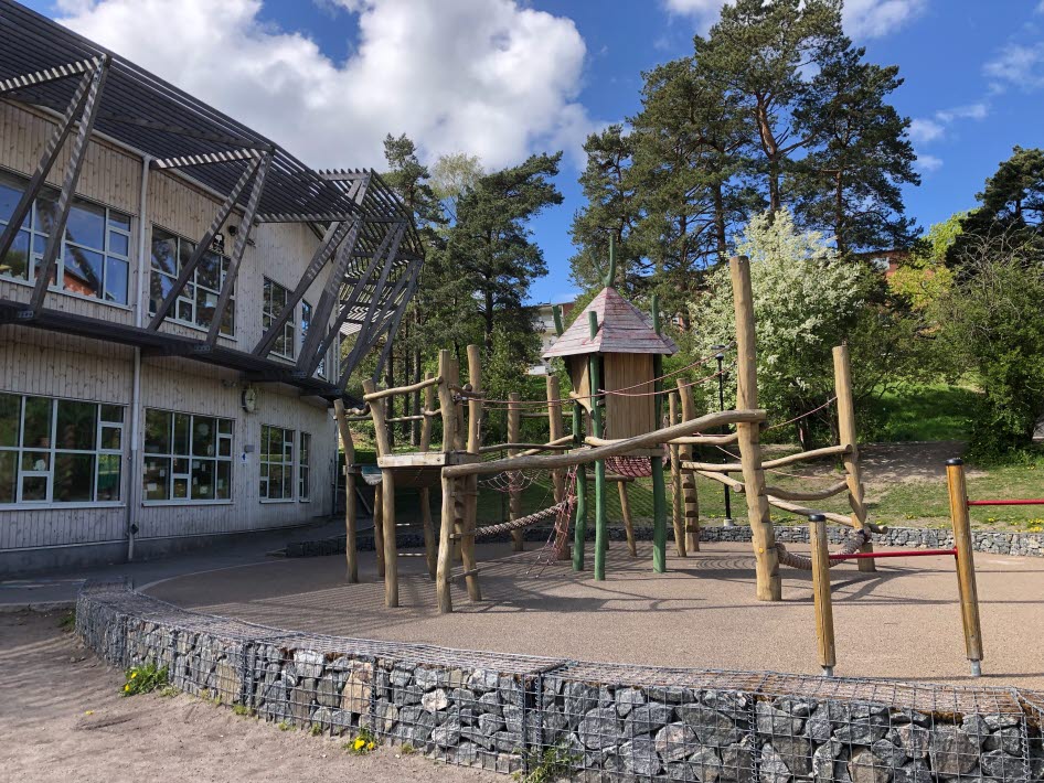 Skolgård med utmanande topografi med stenmurar, trappor, gabioner och slänter. Gården har många träd, men är relativt hårdgjord. Den omgivande naturmarken kompenserar för detta.