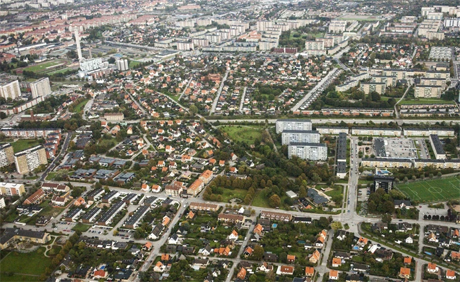 Flygfoto över en stad med tydliga stadsdelar, vägar och gröna områden.