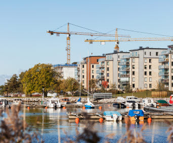 Småbåtshamn med byggkranar bakom flerfamiljshus. Foto: Scandinav/Marie Linnér