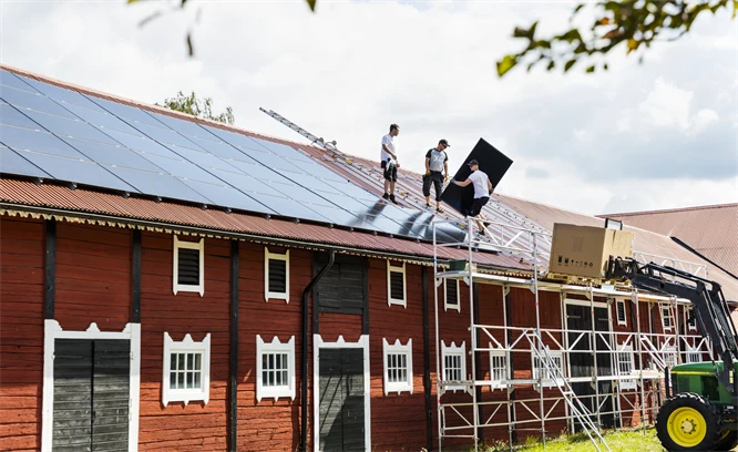 Personer monterar solceller på tak.