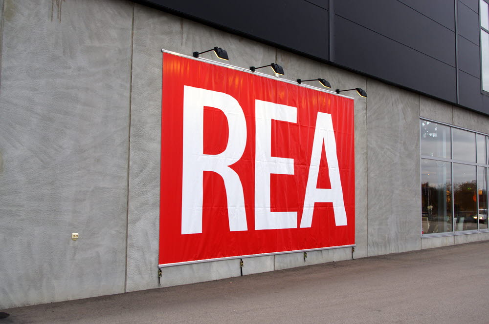Foto av en röd vepa med vit text Rea på en husfasad.