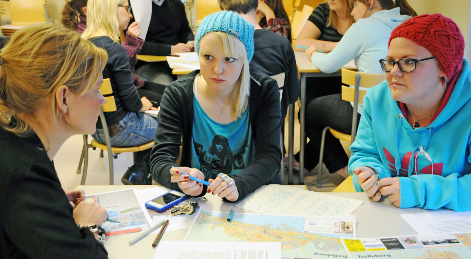 Tre personer som sitter vid ett bord och diskuterar.