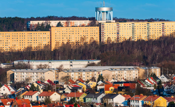 Stadsbild med flerfamiljshus, vattentorn och villor.