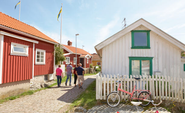 Fyra personer vandrar längs kullerstensgator i en kulturmiljö bland röda och vita trähus. Foto: Anders Järkendal/Scandinav