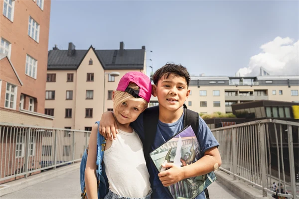 Bild med två pojkar som står framför flerbostadshus.
