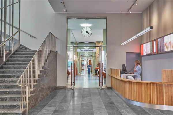 Trapphus med stengolv och en stor reception klädd i trä.
