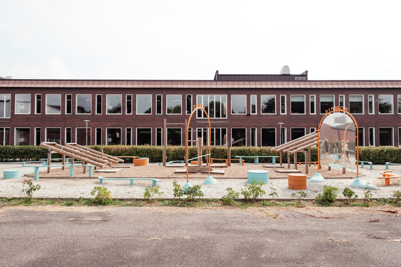 Lekplats framför en skolbyggnad, lekplatsen ligger väldigt nära skolbyggnaden.