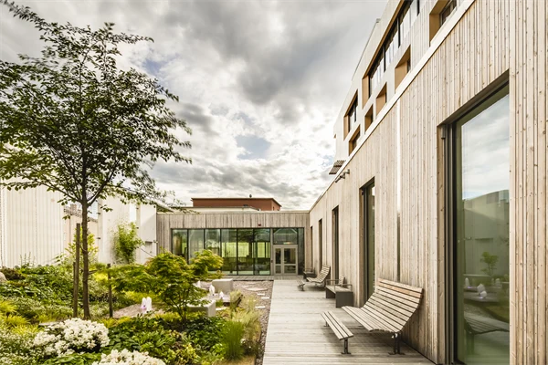 Innergård med planteringar, trädäck och sittbänkar.