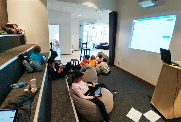 Barn som sitter på gradänger och sittpuffar i ett studierum.