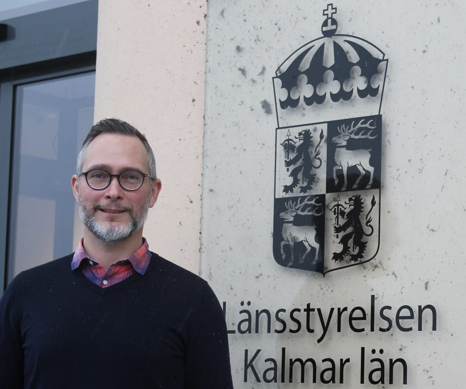 Man utanför byggnad med logotype.