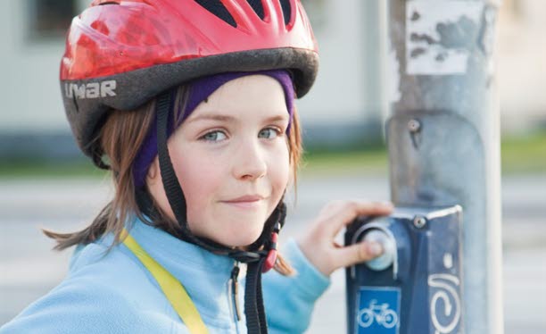 Barn på cykel väntar vid övergångsställe.