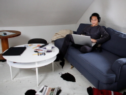 Man i soffa som arbetar med dator i knät. Foto: Peter Kroon
