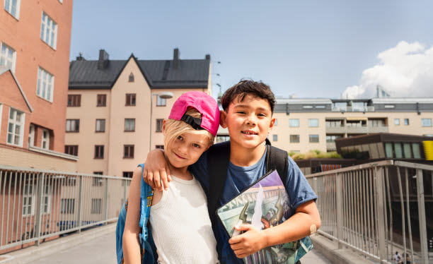 Bild med två pojkar som står framför flerbostadshus.