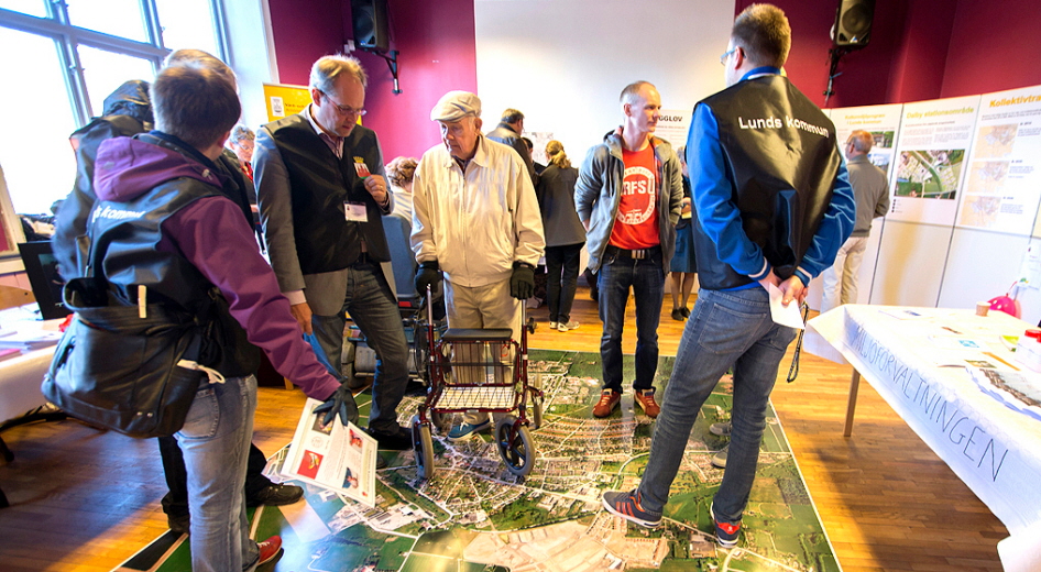 Ett antal personer som tittar på en karta som ligger på gplvet. Foto: Gunnar Menander