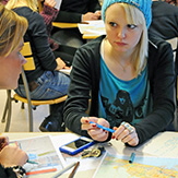En flicka sitter vid ett bord i en skolsal