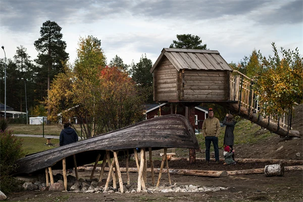 Uppochnervänd båt i trä och en stuga i trä som står på pålar med en landgång som går till den.