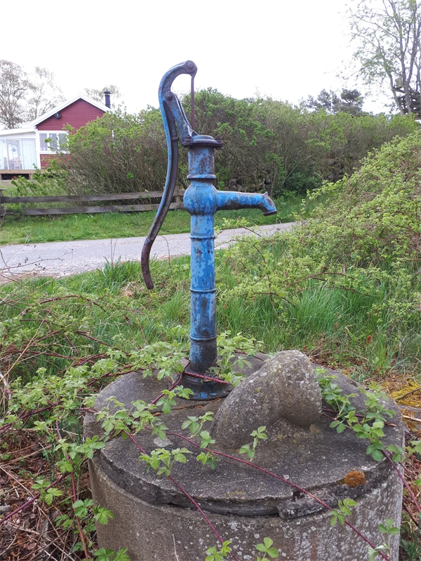 Gammaldags vattenpump vid en brunn.