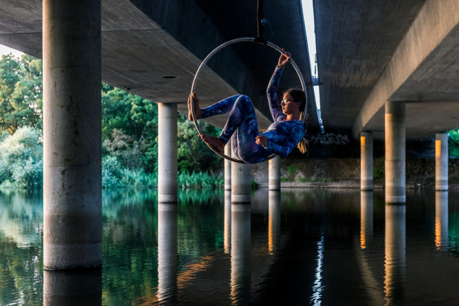Kvinna som sitter i en ring som hänger under en bro